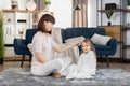 Pretty young mother combing hair of her little daughter after taking bath. Cute child girl wrapped in towel, sitting Royalty Free Stock Photo