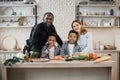 Pretty young mother, father and two children sons preparing salad with fresh vegetables Royalty Free Stock Photo