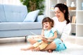 Pretty young mother reading a book to her daughter sitting on the carpet on the floor in the room. Reading with children Royalty Free Stock Photo