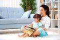 Pretty young mother reading a book to her daughter sitting on the carpet on the floor in the room. Reading with children Royalty Free Stock Photo