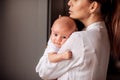 Mother holding her newborn baby standing near the window on the kitchen. Royalty Free Stock Photo