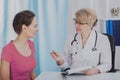 Young patient in medical office of helpful senior female doctor