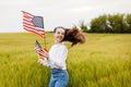 Pretty young pre-teen girl in field holding American flag Royalty Free Stock Photo