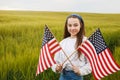 Pretty young pre-teen girl in field holding American flag Royalty Free Stock Photo