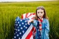 Pretty young pre-teen girl in field holding American flag Royalty Free Stock Photo