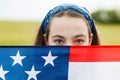 Pretty young pre-teen girl in field holding American flag. Royalty Free Stock Photo