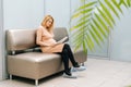 Pretty young pregnant woman is sitting in hallway of hospital waiting to see gynecologist. Royalty Free Stock Photo