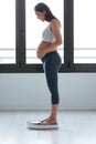 Pretty young pregnant woman standing on scales at home Royalty Free Stock Photo