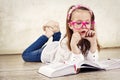 Pretty young schoolgirl reading textbook and wearing glasses Royalty Free Stock Photo