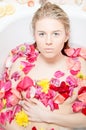 Beautiful blonde lady taking a bath with flower petals Royalty Free Stock Photo