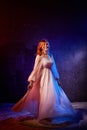 Pretty young sexy model female with blonde hair in amazing long white dress and posing in dark studio Royalty Free Stock Photo