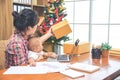 Pretty young single mom working at home on a laptop computer while holding her baby girl sitting on her lap enjoying watching Royalty Free Stock Photo