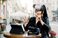 Pretty young smart Caucasian Asian businesswoman, sitting in outdoor cafe in front of tablet, working and watching Royalty Free Stock Photo