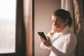 Pretty young smiled Caucasian woman in white turtleneck smiling and videochatting on mobile phone in home.Girl talking Royalty Free Stock Photo