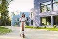 Pretty young smiling girl student riding blue electric kick scooter Royalty Free Stock Photo