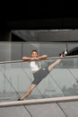 Pretty smiling woman is doing a squat near a transparent glass railing Royalty Free Stock Photo