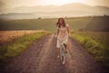 Pretty young smilling woman with retro bicycle in sunset on the road, vintage old times, girl in retro style on meadow Royalty Free Stock Photo