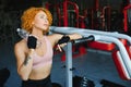 Pretty young sportswoman relaxing after training and drinking water in gym Royalty Free Stock Photo