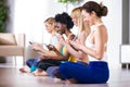 Pretty young sporty women using mobile phone after yoga session at home. Royalty Free Stock Photo
