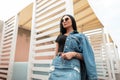 Pretty young stylish woman brunette in a fashionable denim jacket in a vintage skirt in a black top in sunglasses posing Royalty Free Stock Photo