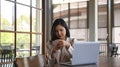 Young stylish woman sitting in front of laptop at coffee shop and using mobile phone. Royalty Free Stock Photo