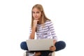 Pretty young teen girl sitting on the floor with crossed legs and using laptop,isolated