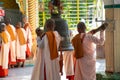 Pretty young teenage nuns in pink uttarasanga hitting a bell in Shwethalyaung reclining buddha temple in Bago Pegu, Myanmar