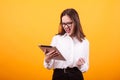 Pretty young teenager can`t contain her happines and holding a tablet in studio over yellow backgroud Royalty Free Stock Photo