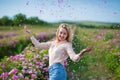 Pretty Young tender woman walking in the tea roses field. Blond lady wearing jeans and retro hat enjoy summer day Royalty Free Stock Photo