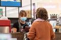 Pretty young waitress with a mask and gloves serving client