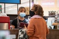 Pretty young waitress with a mask and gloves serving client