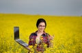 Farmer girl with laptop in rapeseed field Royalty Free Stock Photo