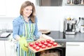 Pretty young woman baking tasty muffins at home