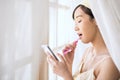 Pretty young woman in bath robe checking news on social media