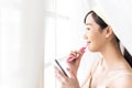 Pretty young woman in bath robe checking news on social media via smartphone