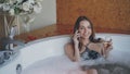 Pretty young woman in bathing suit is talking on mobile phone and drinking champagne while taking bath in spa salon Royalty Free Stock Photo