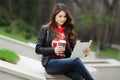 Pretty young woman with beautiful smile using tablet in the park at the sunset. Royalty Free Stock Photo