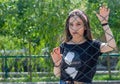 Pretty young woman behind fence, young woman in a park Royalty Free Stock Photo