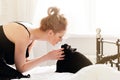 Pretty young woman with black cat in blanket in white bedroom Royalty Free Stock Photo