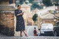 Pretty young woman in a black dress using smartphone at old town street. Travel by Europe.