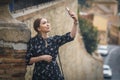 Pretty young woman in a black dress using smartphone at old town street. Travel by Europe.