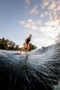 Pretty young woman rides down on surf style wakeboard on splashed river wave Royalty Free Stock Photo