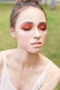 Pretty young woman with bright make up. Outdoor green portrait