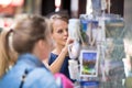 Pretty, young woman buying a postcard on a street