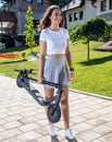 Pretty young woman carrying her folded electric scooter as she gets ready to take a ride Royalty Free Stock Photo