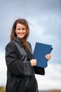 Pretty, young woman celebrating joyfully her graduation - spreading wide her arms, holding her diploma