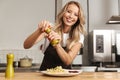 Pretty young woman chef putting salt Royalty Free Stock Photo