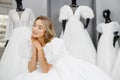 Pretty young woman is choosing a wedding dress in the shop. The bride-to-be is wearing a wedding dress for fitting Royalty Free Stock Photo