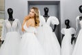 Pretty young woman is choosing a wedding dress in the shop. The bride-to-be is wearing a wedding dress for fitting Royalty Free Stock Photo