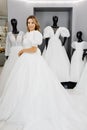 Pretty young woman is choosing a wedding dress in the shop. The bride-to-be is wearing a wedding dress for fitting Royalty Free Stock Photo